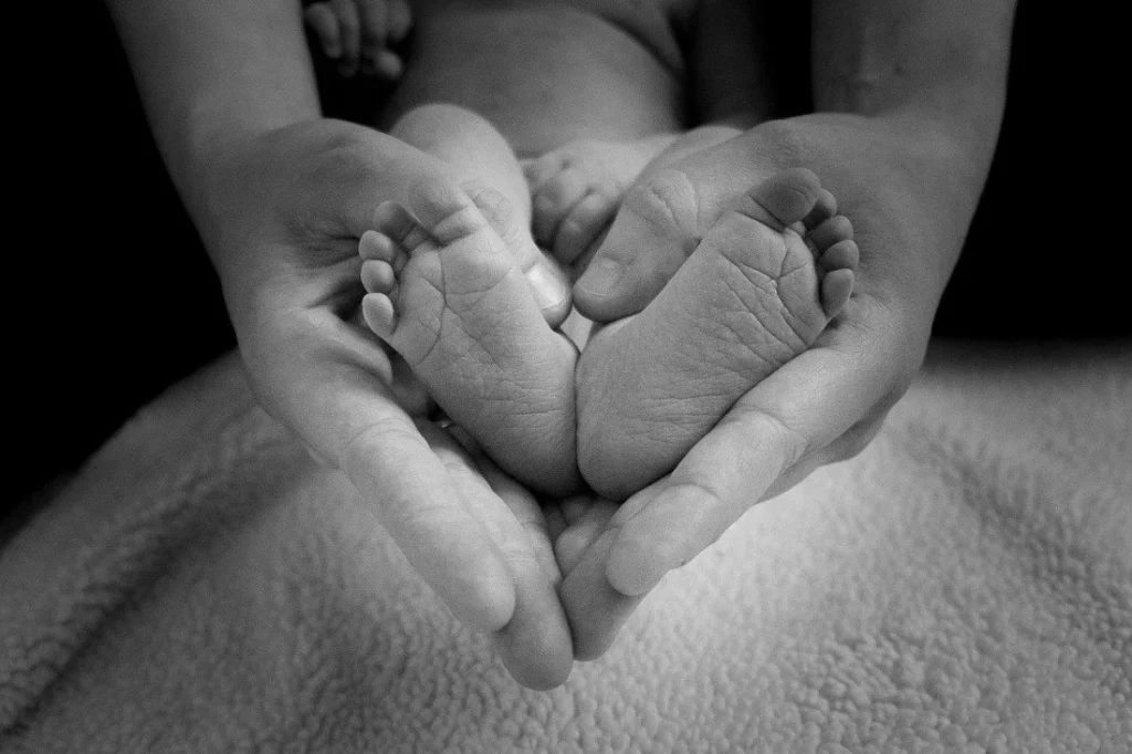 Séance de réflexologie plantaire bébé à Caen : les mains de la praticienne enveloppent les pieds d’un nourrisson